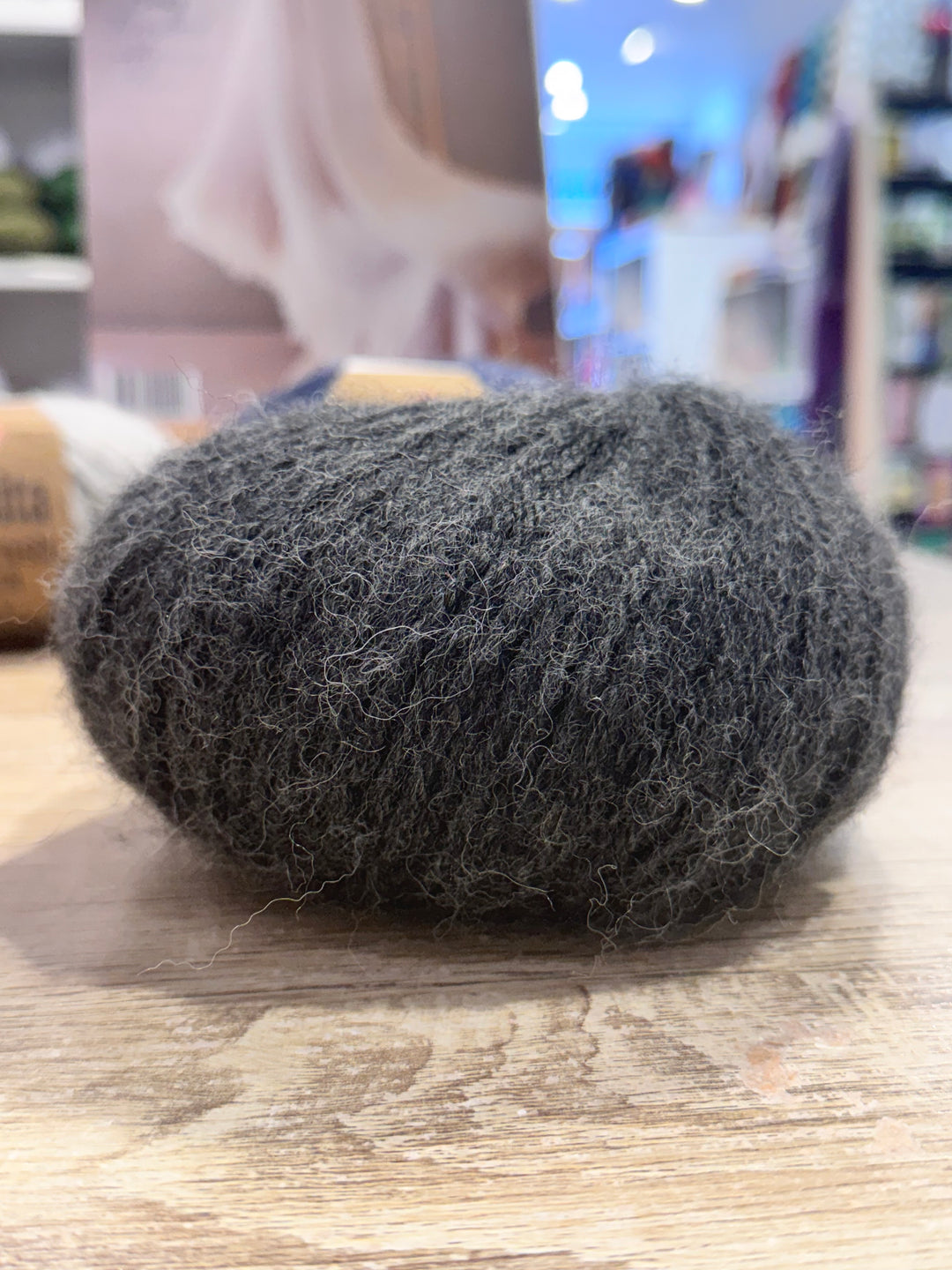 Grey alpaca yarn on a wooden surface with a blurred background