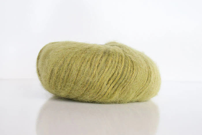 Ball of green alpaca yarn on a white background