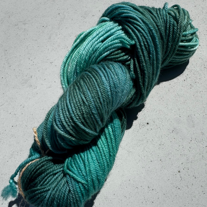 Turquoise skein of yarn on a concrete surface