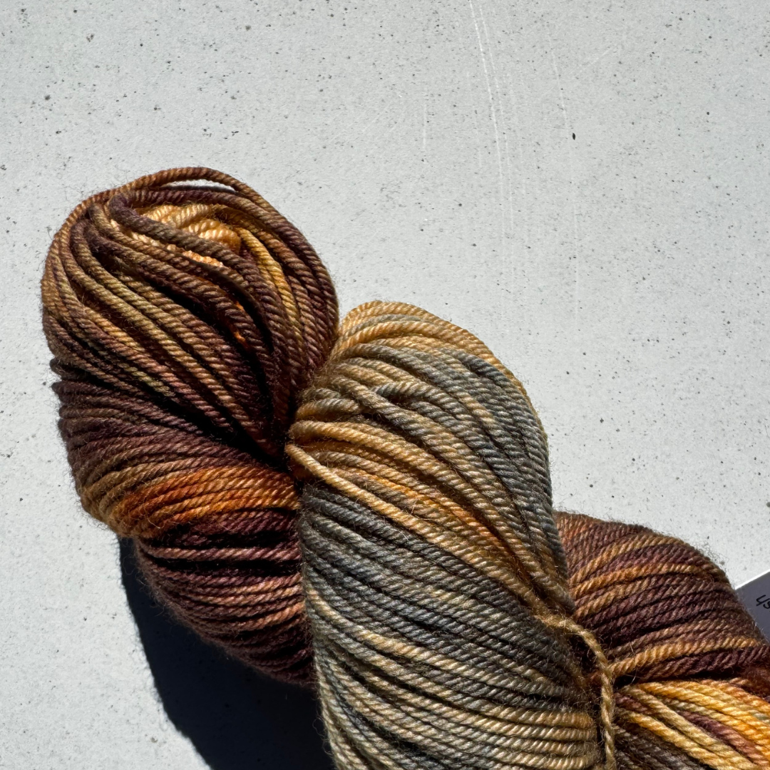 one skeins of brown and olive multicolored yarn on a light gray background