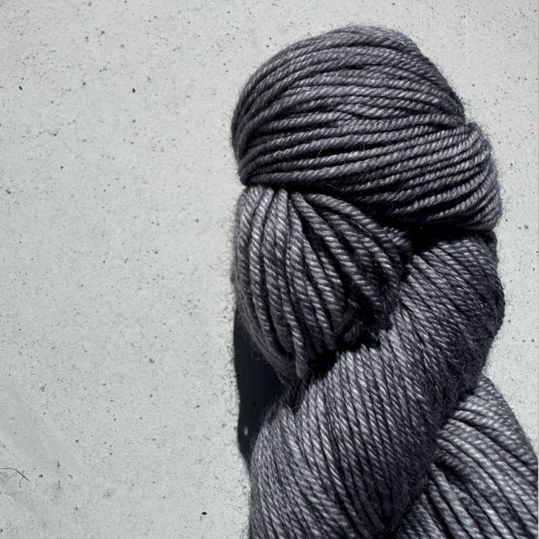 Gray skein of yarn on a light gray concrete surface