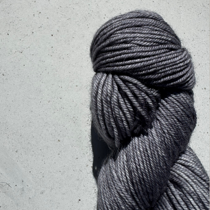 Gray skein of yarn on a light gray concrete surface