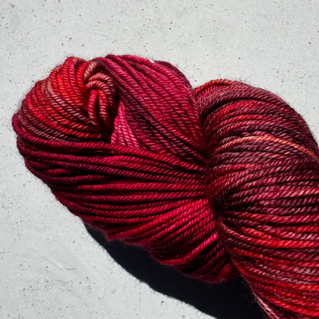 The red raspberry Red skein of yarn on a light gray background