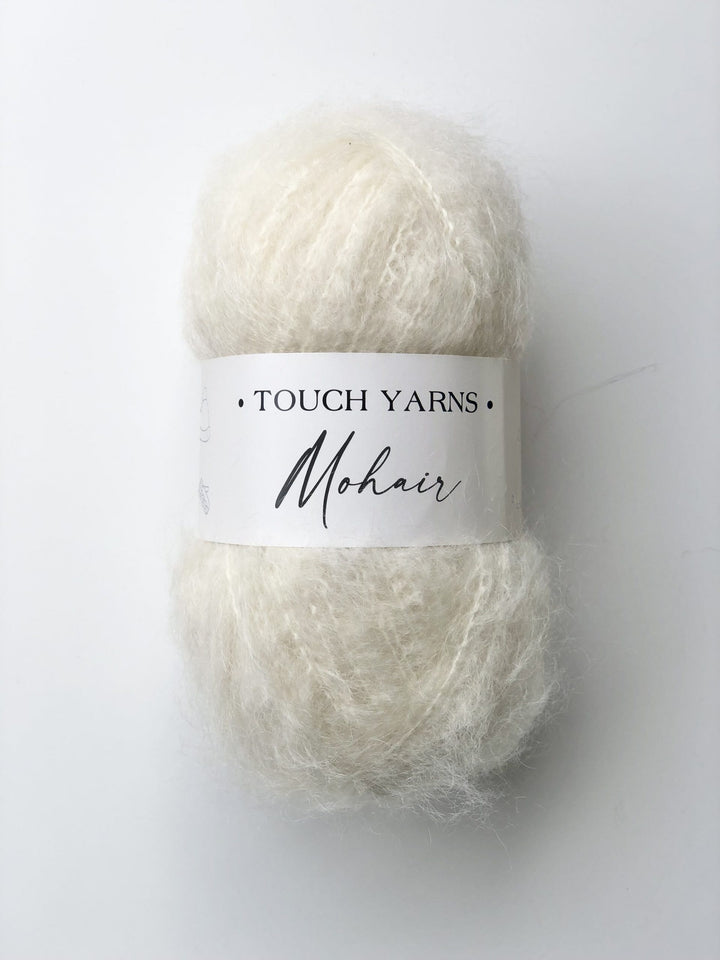 Ball of white yarn with 'Touch Yarns' label on a white background