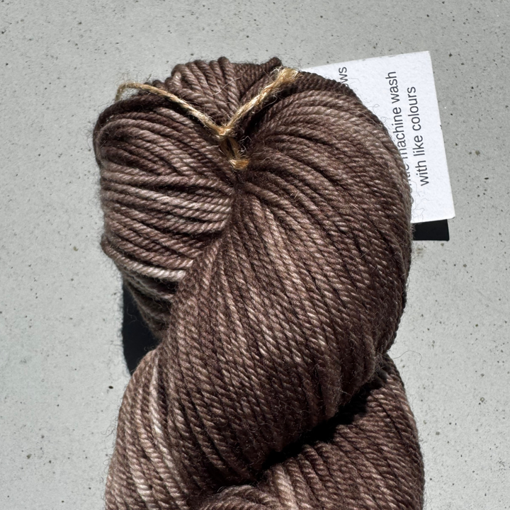 Brown skein of yarn with a label on a gray surface