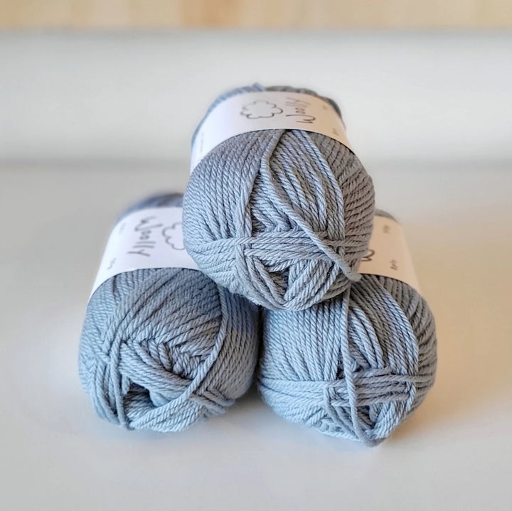 Three balls of gray yarn stacked on a light background