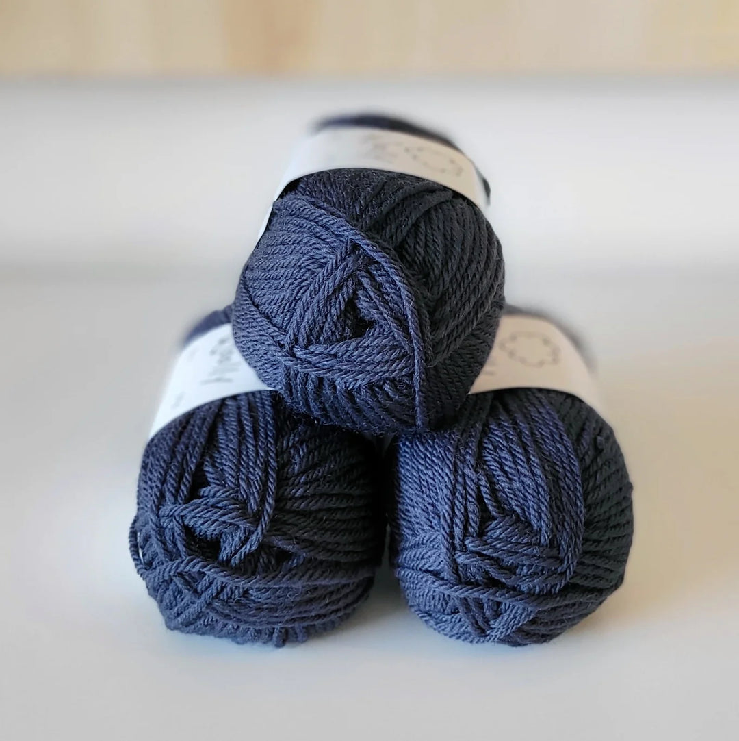 Three skeins of dark blue yarn on a light background
