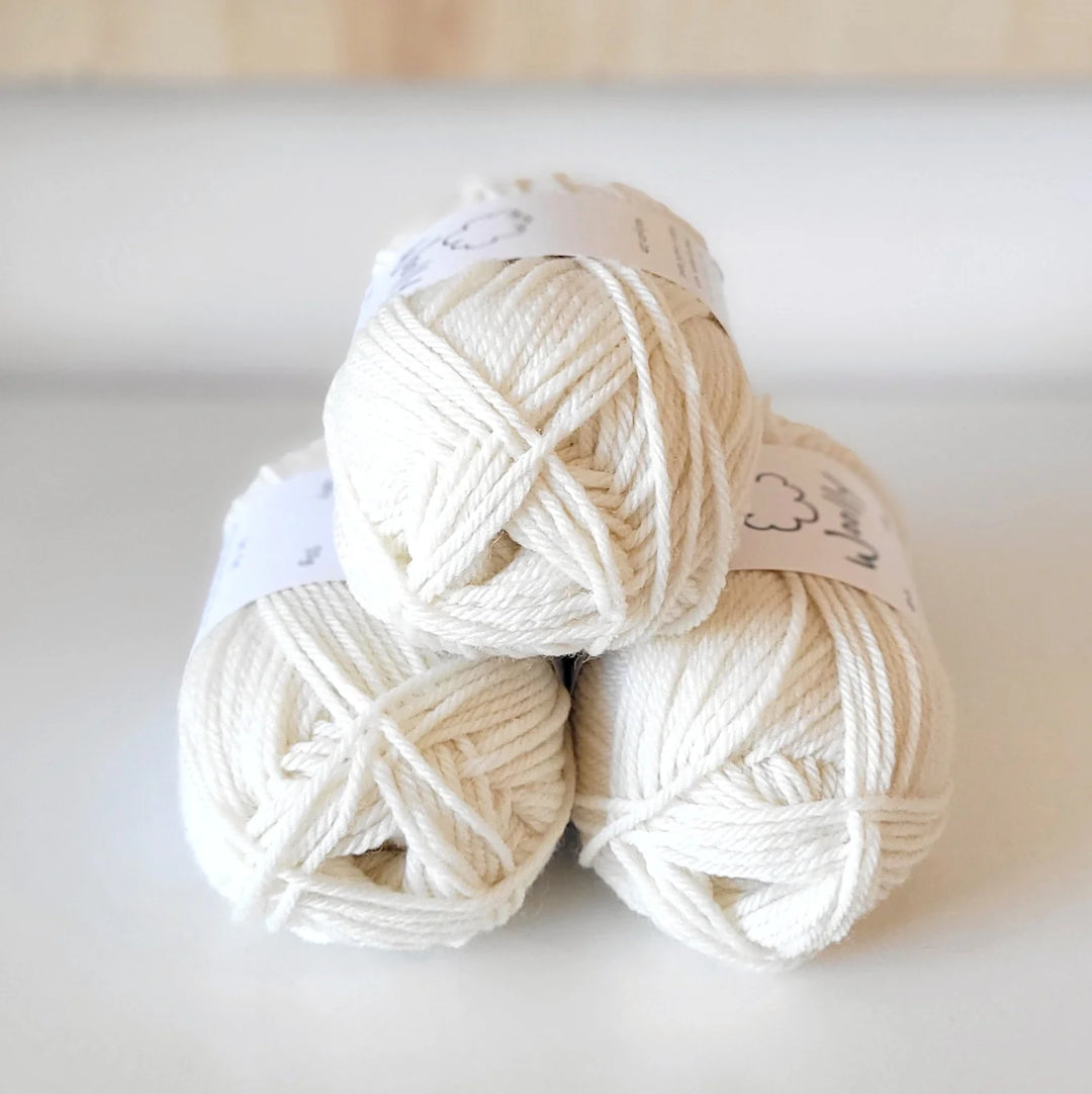 Three balls of cream-colored yarn on a light background
