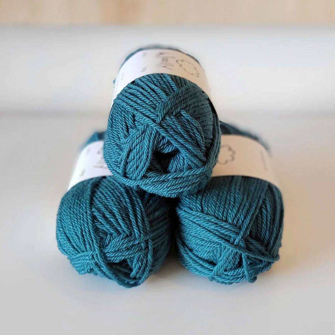 Three skeins of teal yarn on a light background