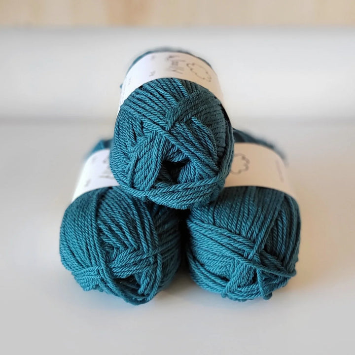 Three skeins of teal yarn on a light background