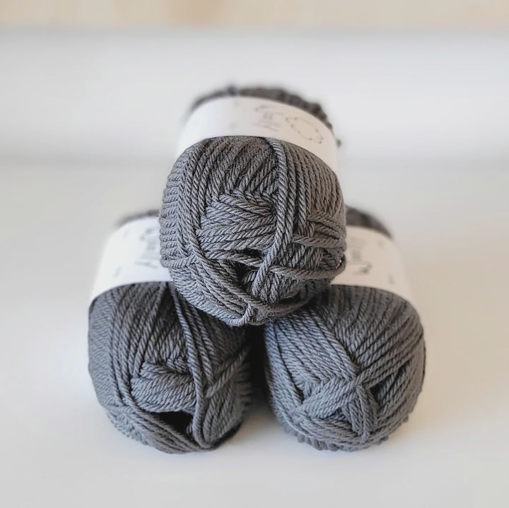 Three skeins of gray yarn stacked on a white surface