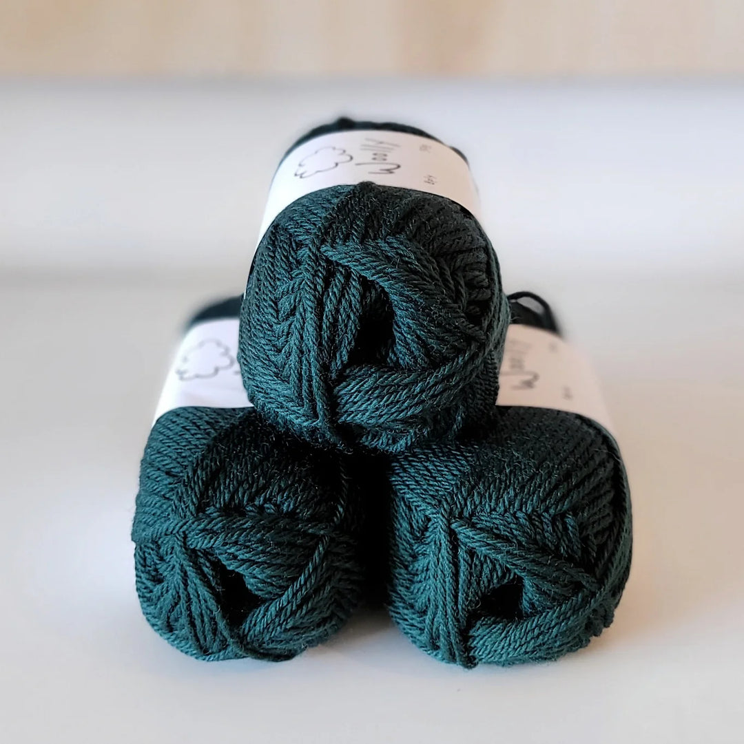Three skeins of teal yarn stacked on a light background