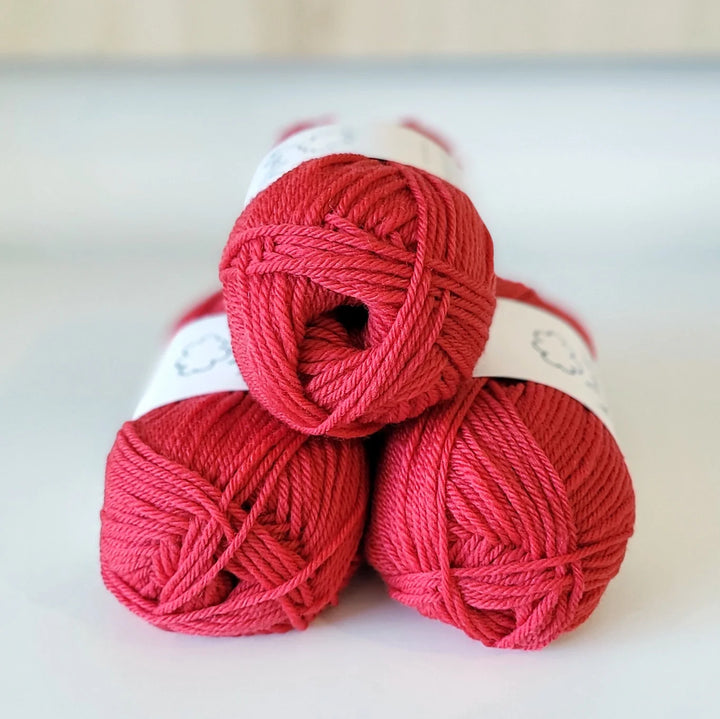Three red skeins of yarn stacked on a light background