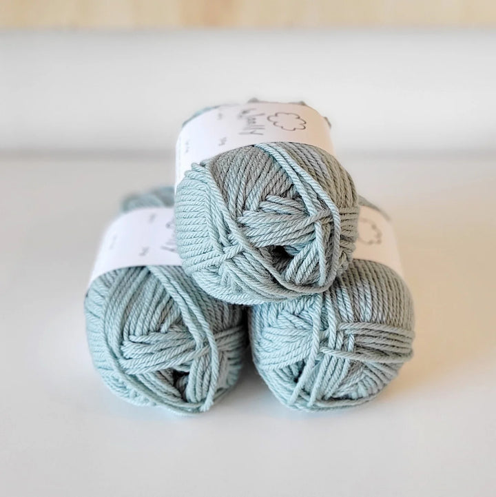 Three skeins of light blue yarn stacked on a white surface