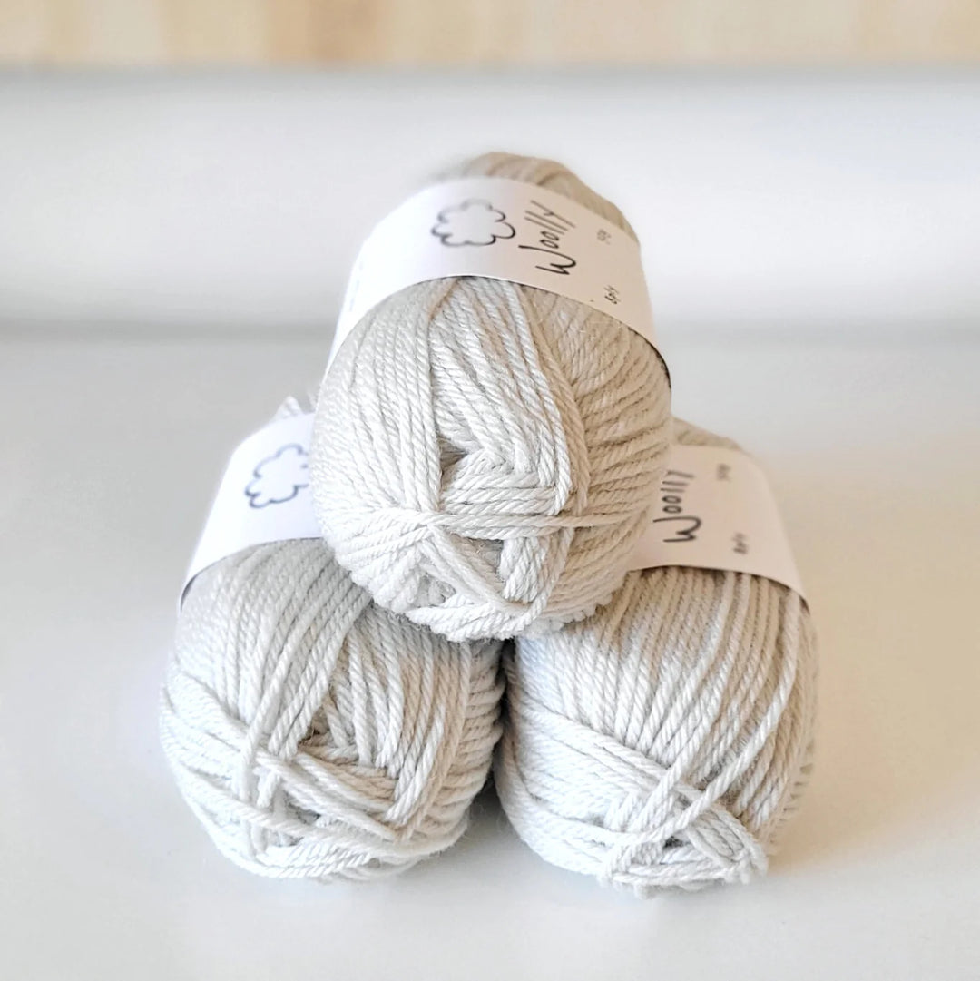Three balls of white yarn stacked on a light background