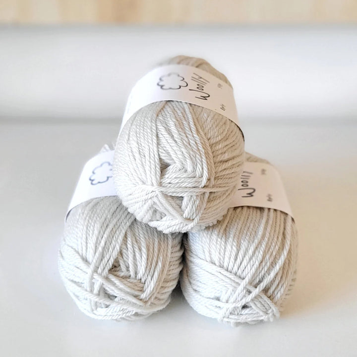 Three balls of white yarn stacked on a light background