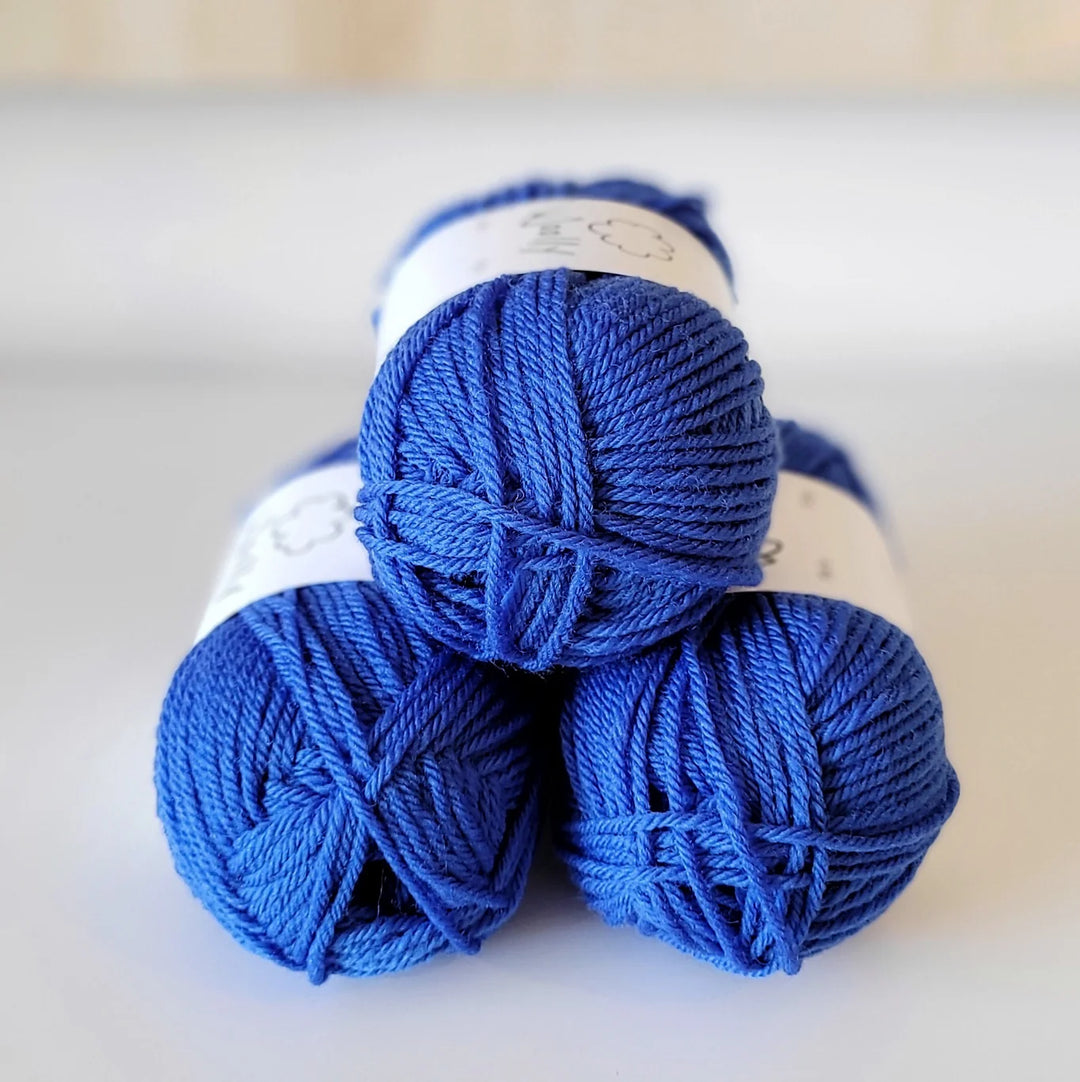 Three blue skeins of yarn stacked on a light background
